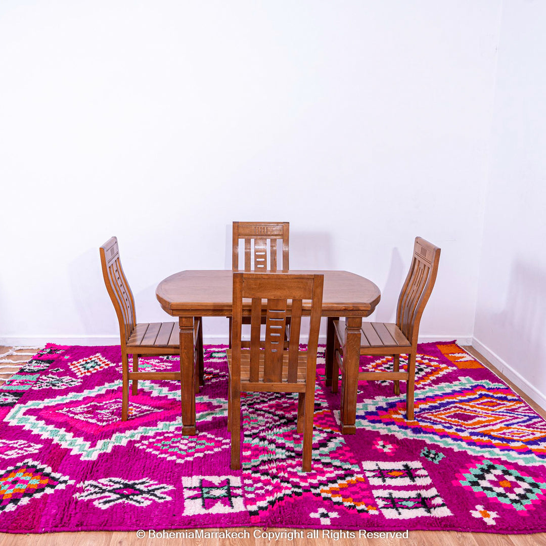Pink Azilal Moroccan rug with geometric patterns under wooden dining set. Handcrafted wool carpet from Morocco.