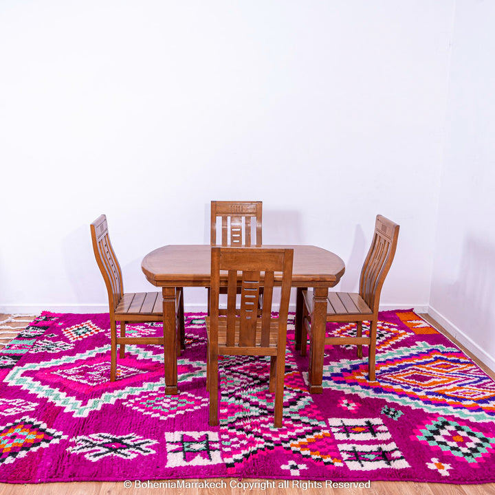 Pink Azilal Moroccan rug with geometric patterns under wooden dining set. Handcrafted wool carpet from Morocco.