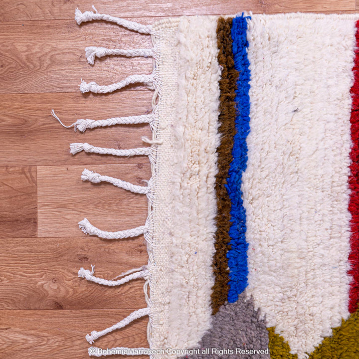 Close-up of colorful geometric Azilal rug with blue, red, and olive stripes on an ivory background. Moroccan Berber wool rug.