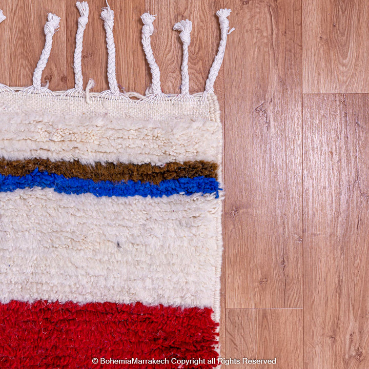 Colorful Moroccan wool rug with geometric stripes in red, blue, and brown on ivory, showcasing traditional Berber design.