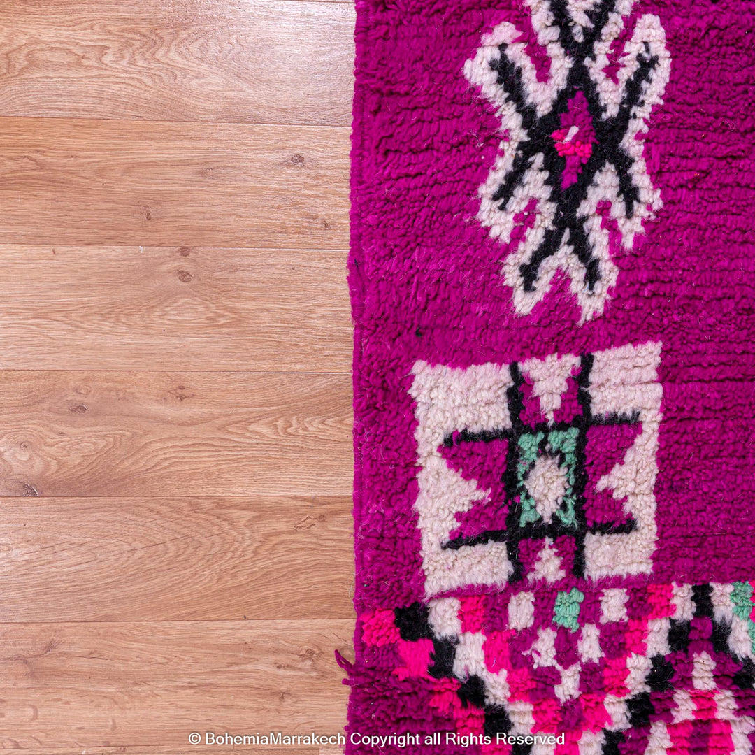 Colorful Pink Azilal Moroccan Rug with geometric tribal motifs on fuchsia background, handcrafted wool carpet.