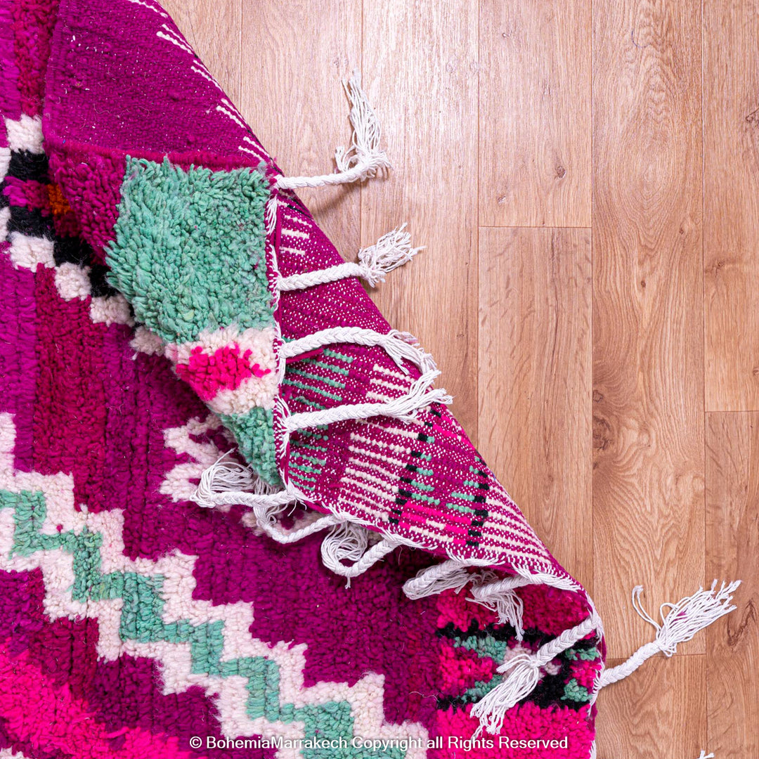 Pink Azilal Moroccan rug with vibrant geometric patterns, handmade from wool. Colorful design with turquoise, orange, and violet.