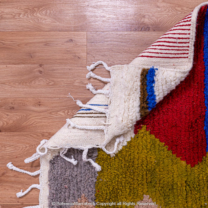 Colorful geometric Azilal Moroccan rug with diamond shapes in red, yellow, blue on ivory, handmade wool. Perfect for bohemian decor.