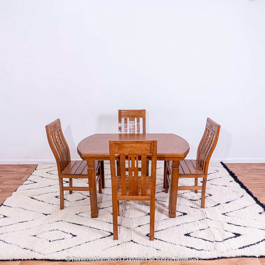 Black and white diamond Moroccan rug under wooden dining table and chairs, featuring traditional Berber design and handmade wool.