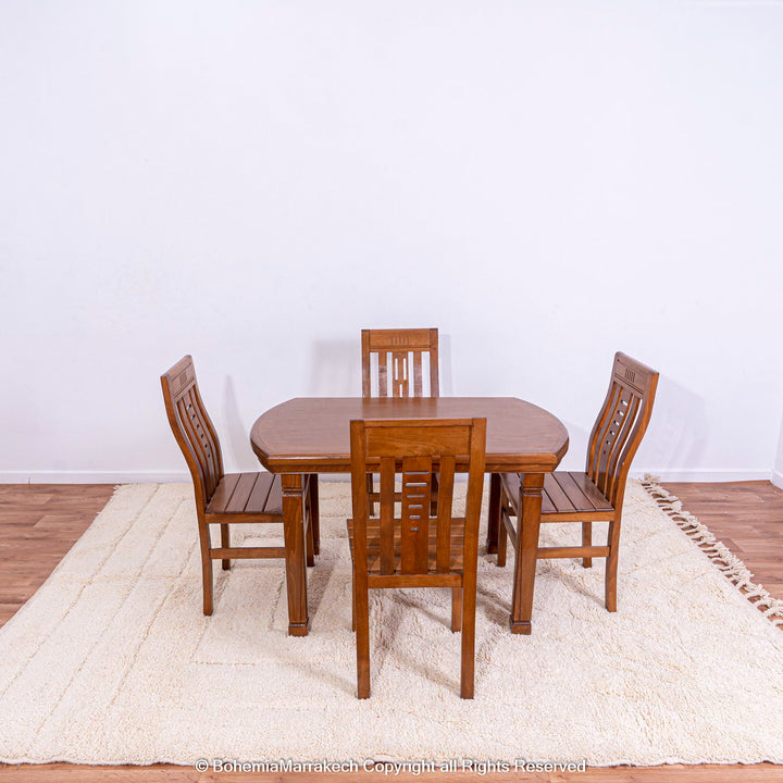 Wooden dining set on cream Moroccan Berber rug with geometric pattern.