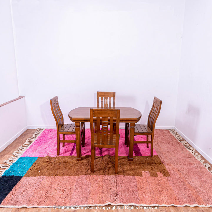 Handmade Moroccan rug with pink, blue, and brown geometric design under dining table, showcasing wool shag texture and modern Moroccan style.