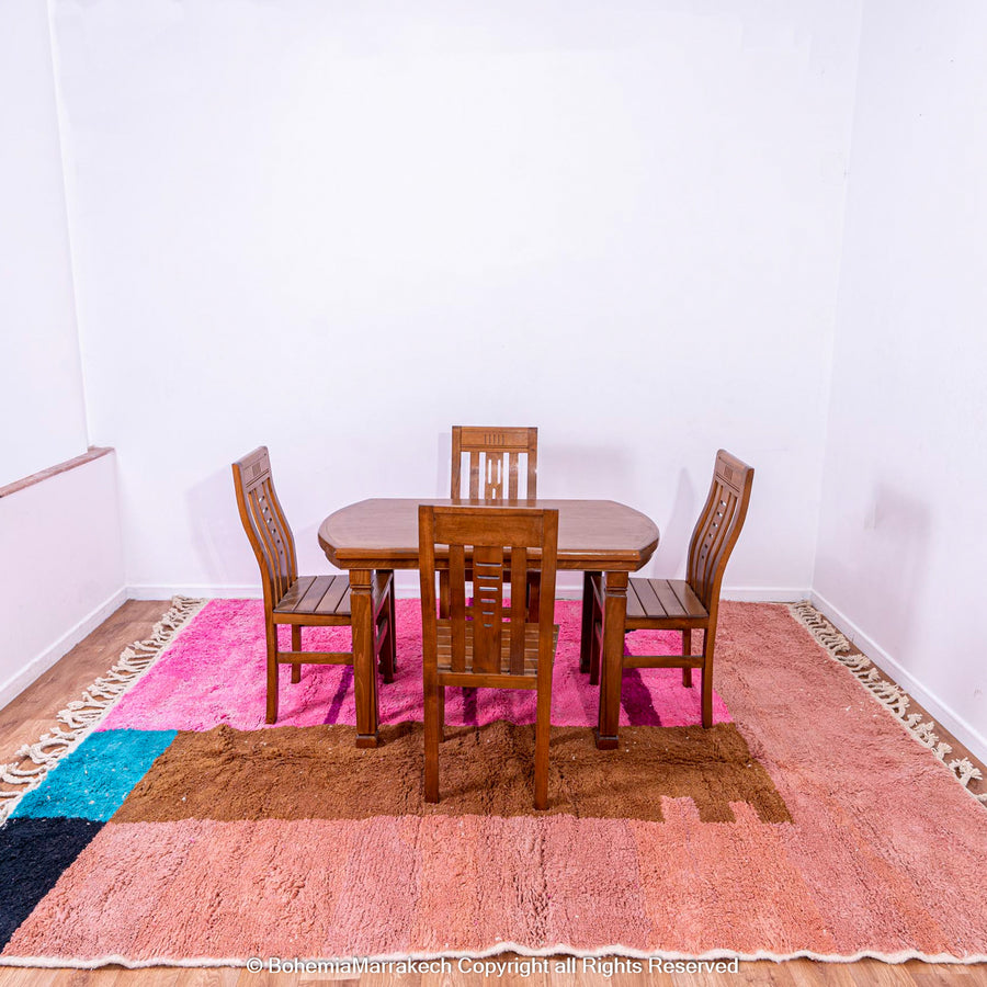Handmade Moroccan rug with pink, blue, and brown geometric design under dining table, showcasing wool shag texture and modern Moroccan style.