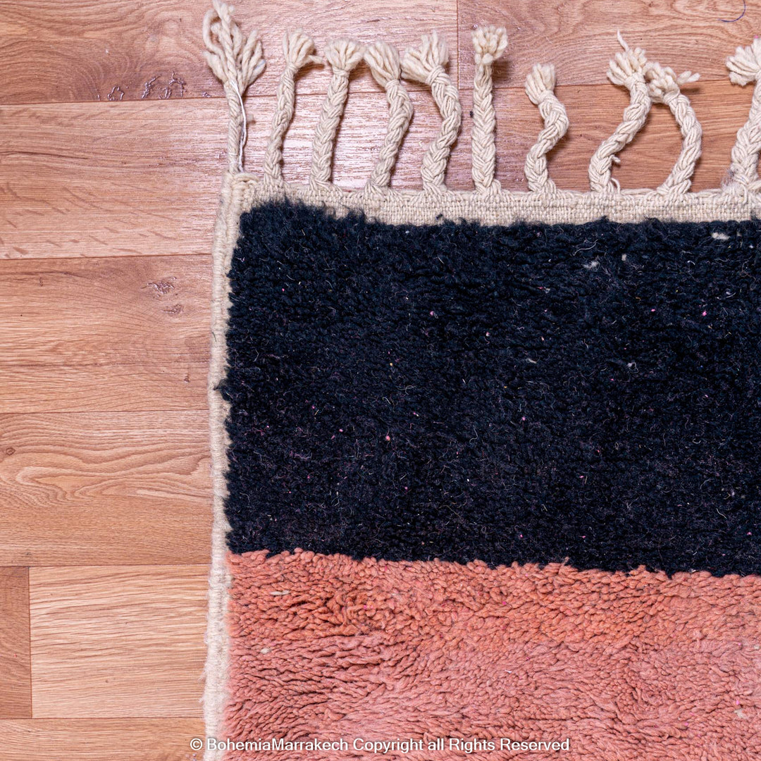 Handmade Moroccan rug with colorful wool shag and geometric design on wooden floor.