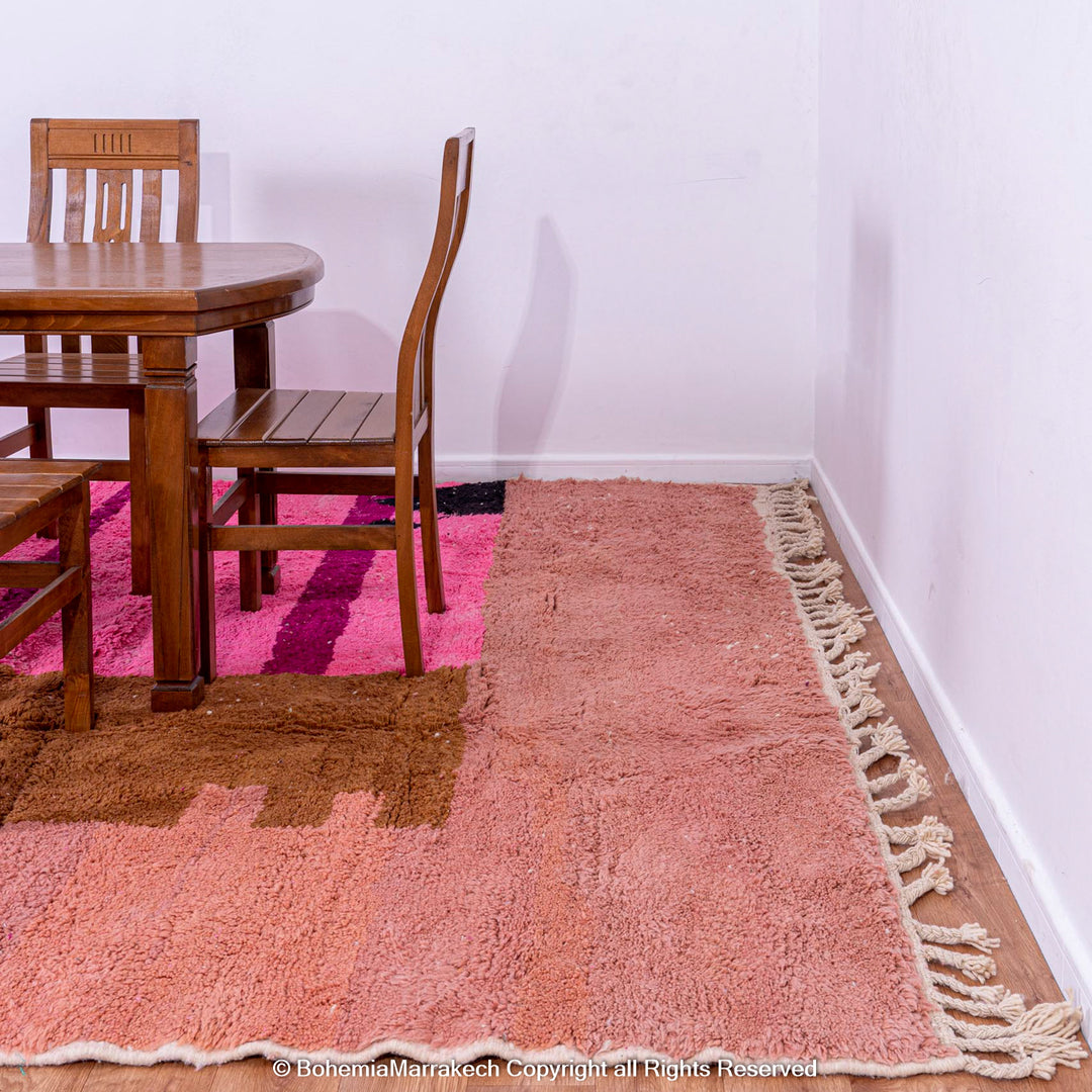 Handmade Moroccan wool shag rug with colorful geometric design under dining table, showcasing pink and brown blocks. Moroccan style decor.