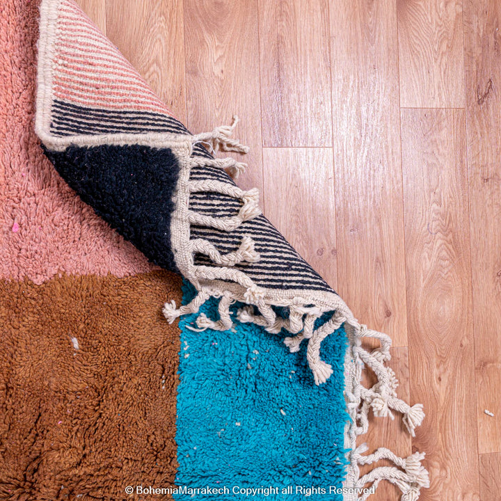 Handmade Moroccan wool rug with geometric design in pink, blue, and brown, showcasing traditional craftsmanship. Moroccan rugs for sale.