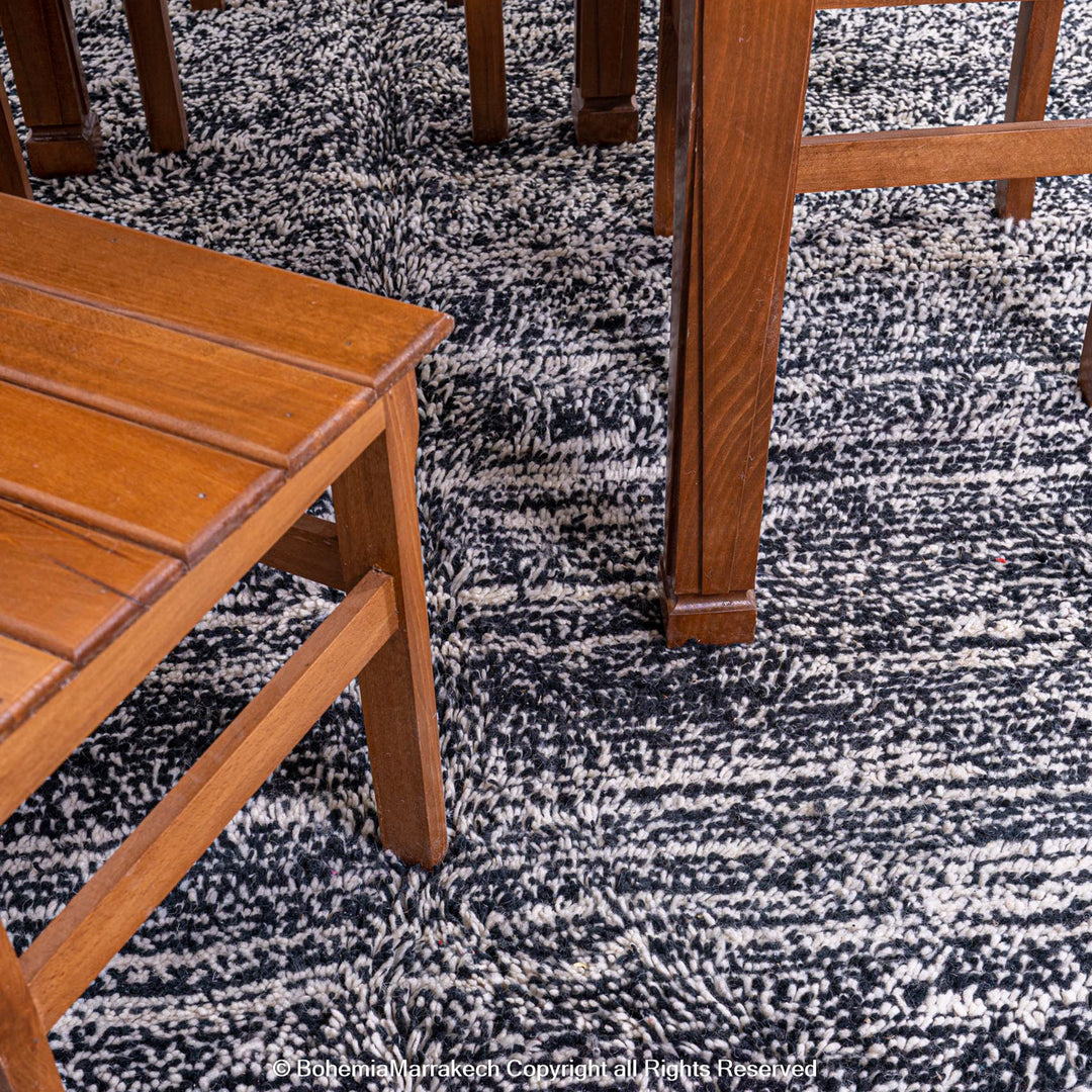Handmade Grey Moroccan Berber Rug featuring marbled dark grey and white tones under wooden furniture, a modern and elegant decor piece.