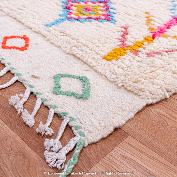 Colorful Moroccan rug with diamond Berber pattern and vibrant symbols on a cream base, handmade from natural wool.
