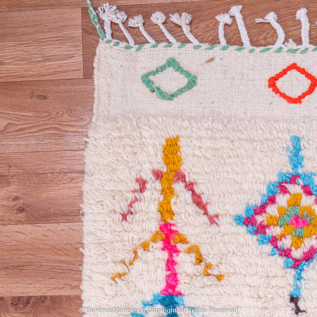 Colorful Moroccan rug with diamond Berber pattern, featuring vibrant pink, blue, yellow, and orange symbols on a cream wool base.