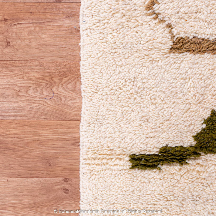 Close-up of a colorful Moroccan Berber rug with abstract camel design on wooden floor.