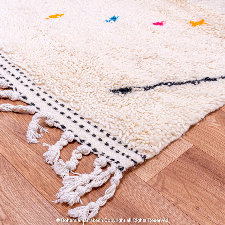 Close-up of a colorful Azilal Moroccan wool rug with tribal designs and vibrant detailing on a wooden floor.