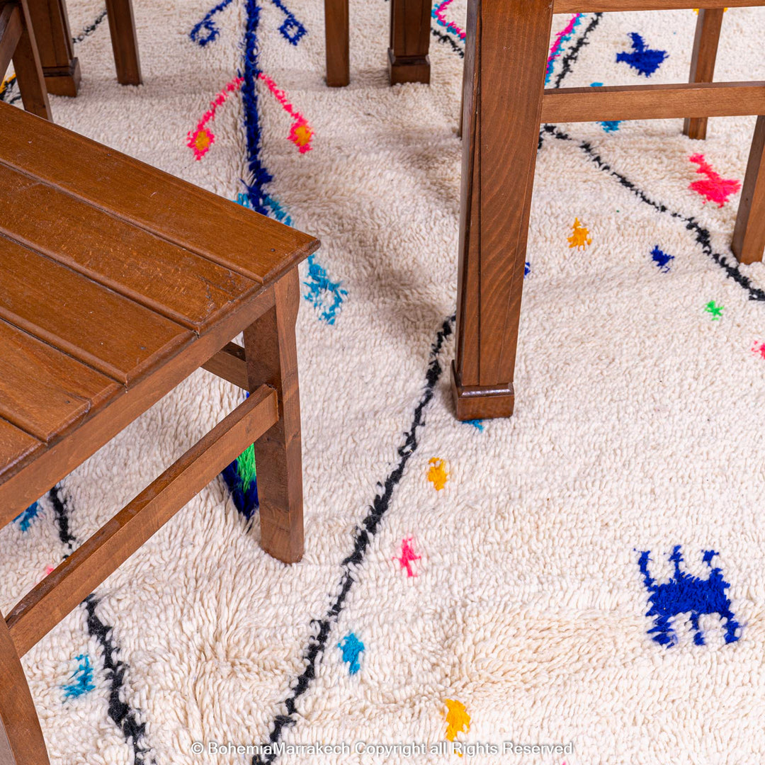 Colorful Azilal Moroccan wool rug under wooden furniture, featuring vibrant diamond motifs and traditional Berber designs.