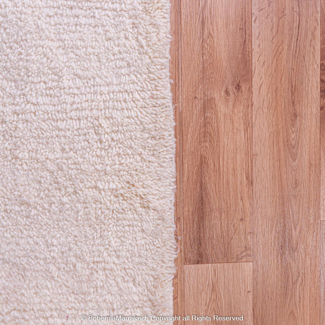 Close-up of a Moroccan wool rug on wooden floor, showcasing texture.