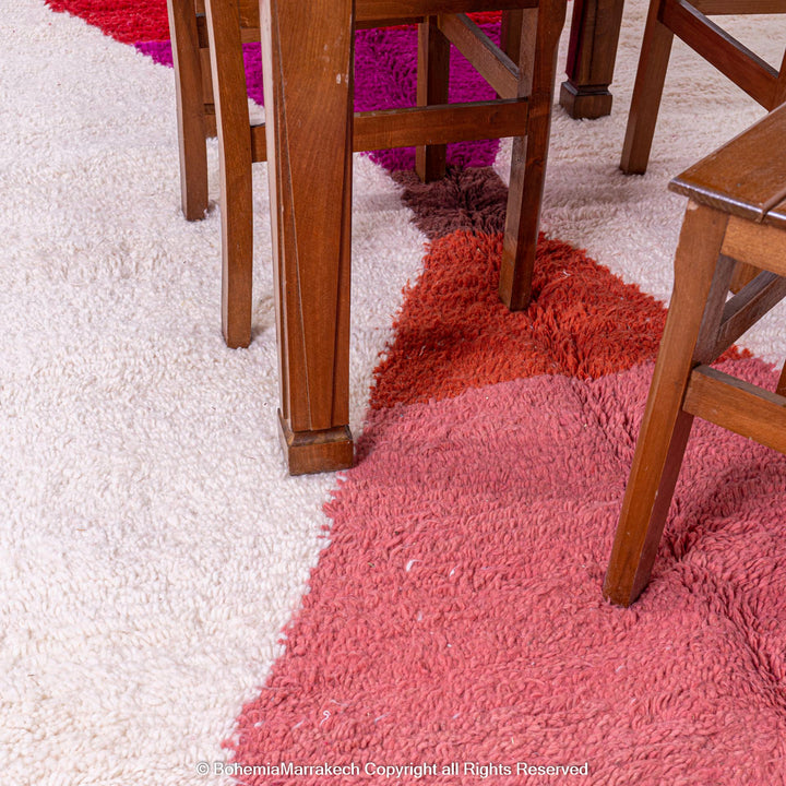 Red and pink handmade Moroccan wool rug with hourglass design under dining table
