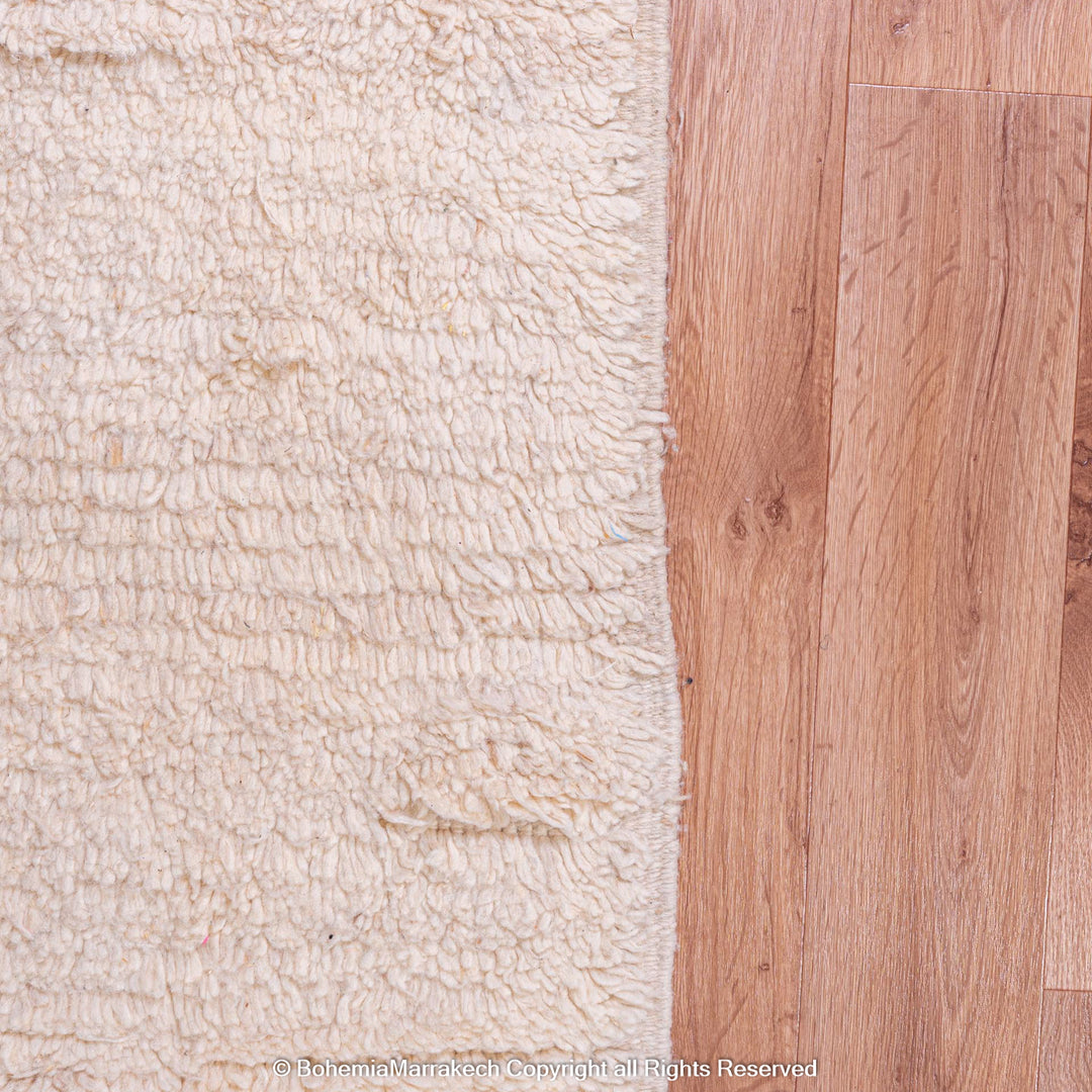 Close-up of creamy Moroccan wool rug on wooden floor