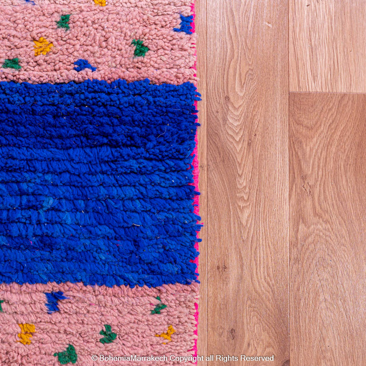 Pink and blue Moroccan rug with multicolor specks and geometric white lines