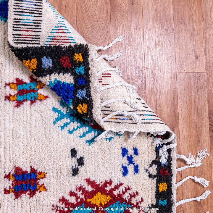 White Moroccan wool rug with colorful Berber tribal motifs and dark border – Beni Ourain handmade