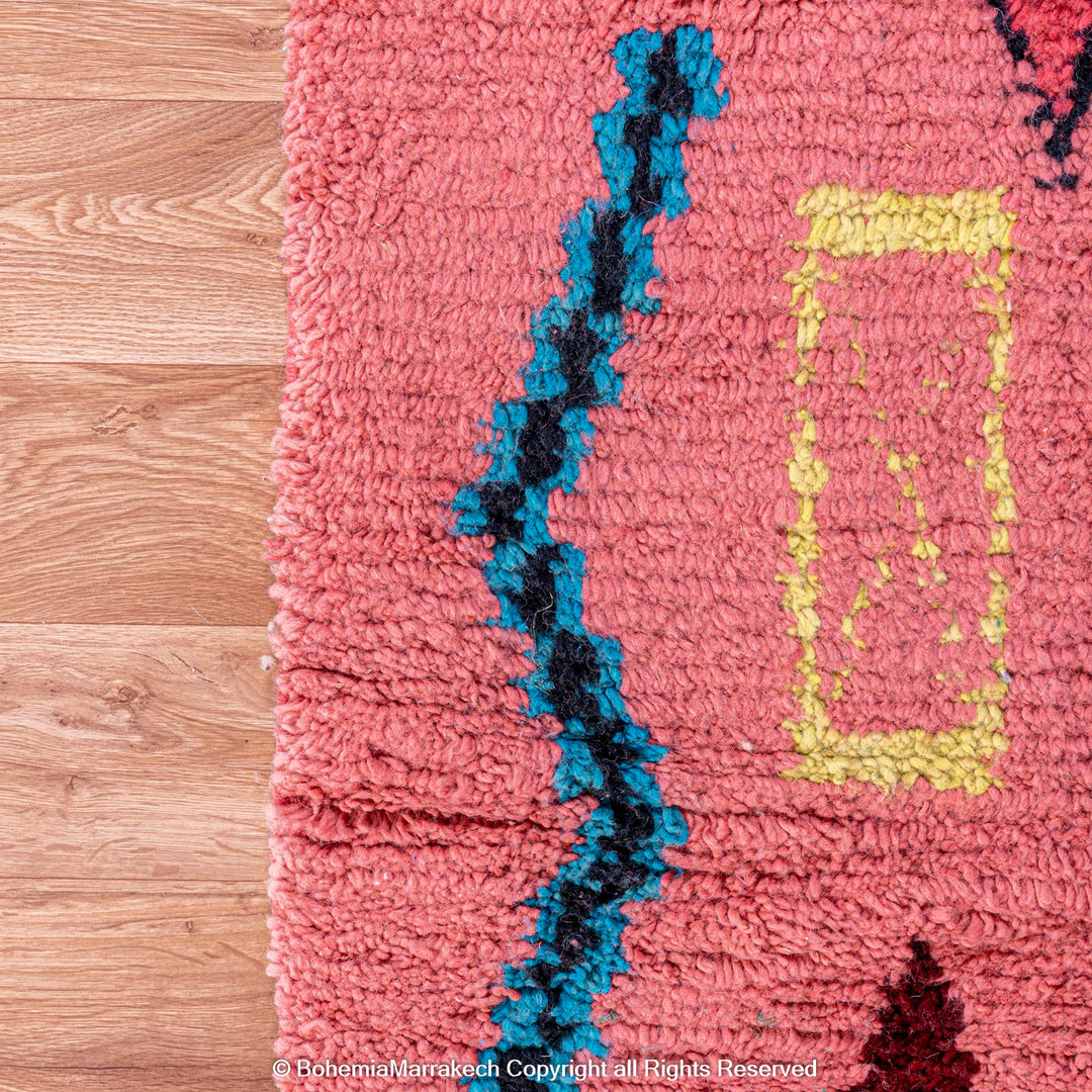 Colorful bright pink Moroccan wool rug with blue and yellow diamond patterns