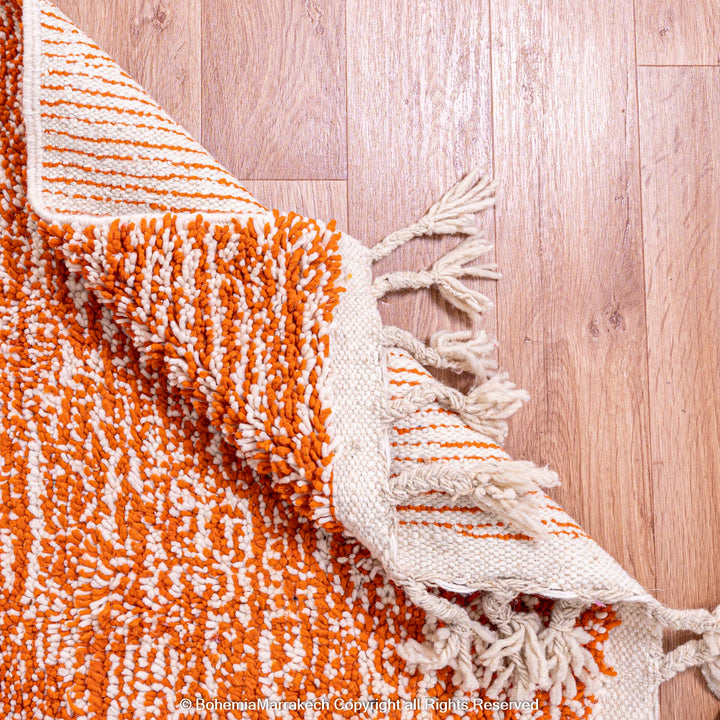 Colorful Moroccan rug with orange base and geometric wool patterns in black, cream, turquoise, and pink