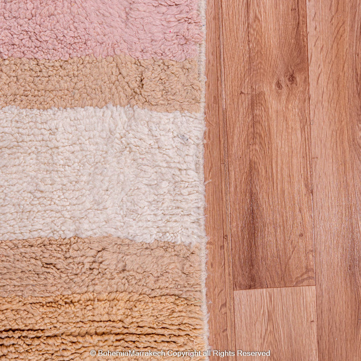 Handmade colorful striped Moroccan wool rug on wooden floor.