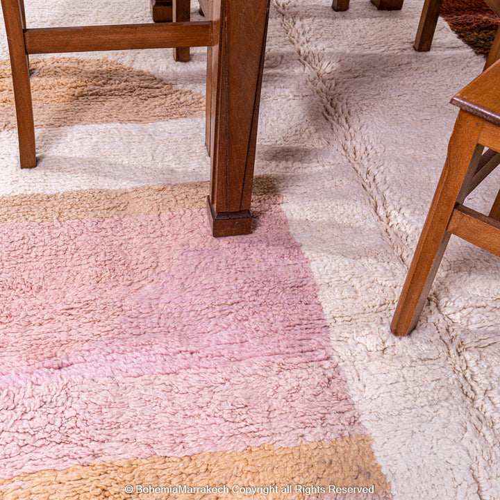 Colorful striped Moroccan rug, handmade with wool, featuring earth tones and pastels, under a wooden dining table.
