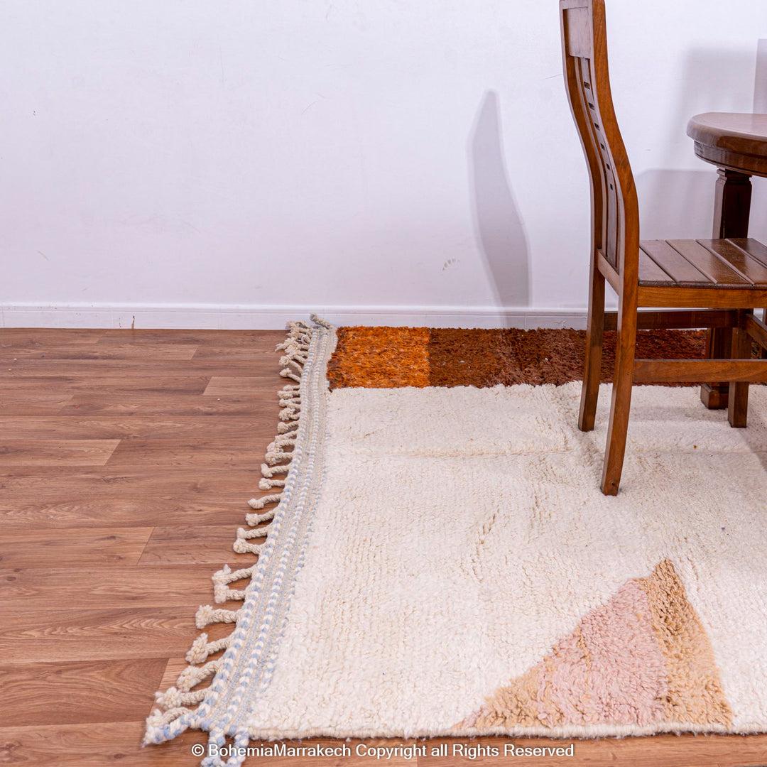 Colorful striped Moroccan Berber rug with natural wool in warm earth tones, shown in a dining room setting.