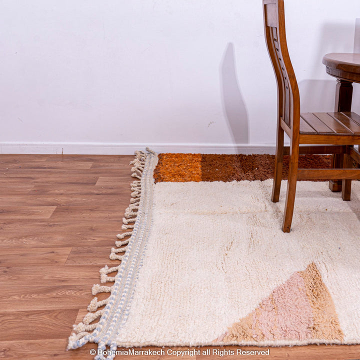 Colorful striped Moroccan Berber rug with natural wool in warm earth tones, shown in a dining room setting.