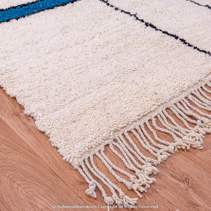 Modern Moroccan Beni Ourain wool rug with color blocks and black lines, handwoven in Morocco on a wood floor.