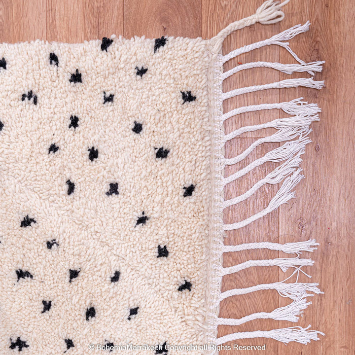White Moroccan Beni Ourain rug with black dots, handcrafted from 100% natural wool by Berber artisans; perfect for modern interiors.