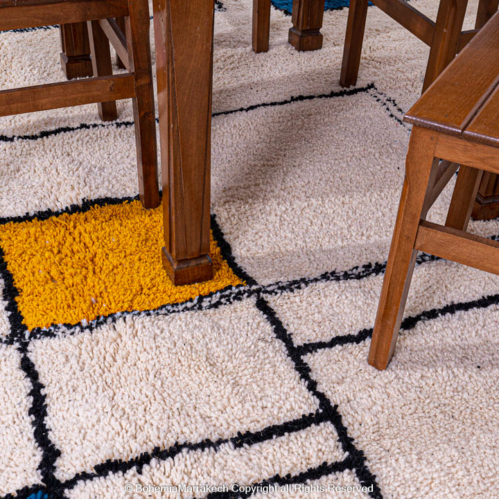 Modern Moroccan wool rug with colorful blocks and black lines under wooden furniture, showcasing a Beni Ourain style.