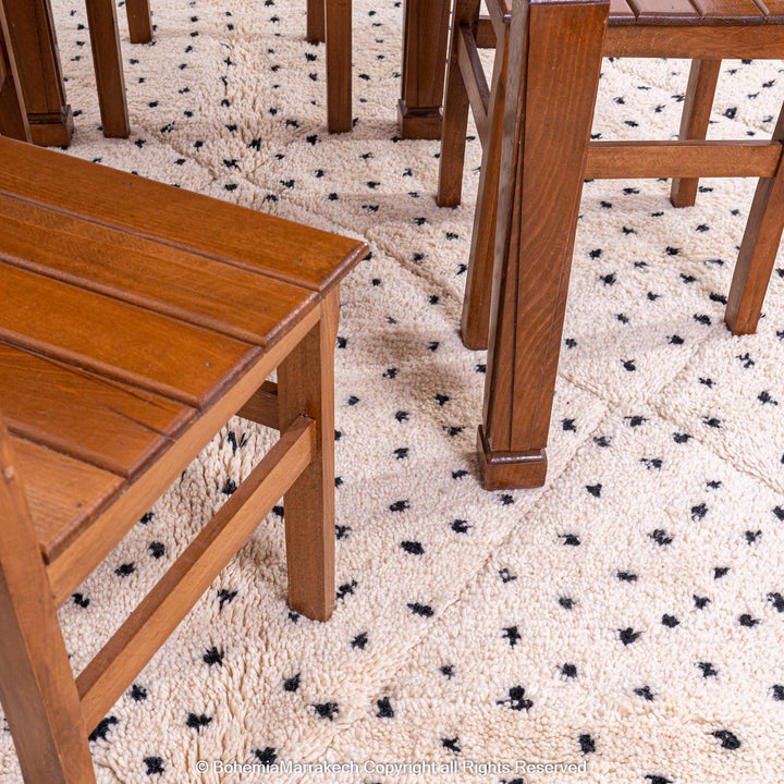 White Moroccan Beni Ourain rug with black dots under wooden chairs, handcrafted wool by Berber artisans. Moroccan rug 8x10.