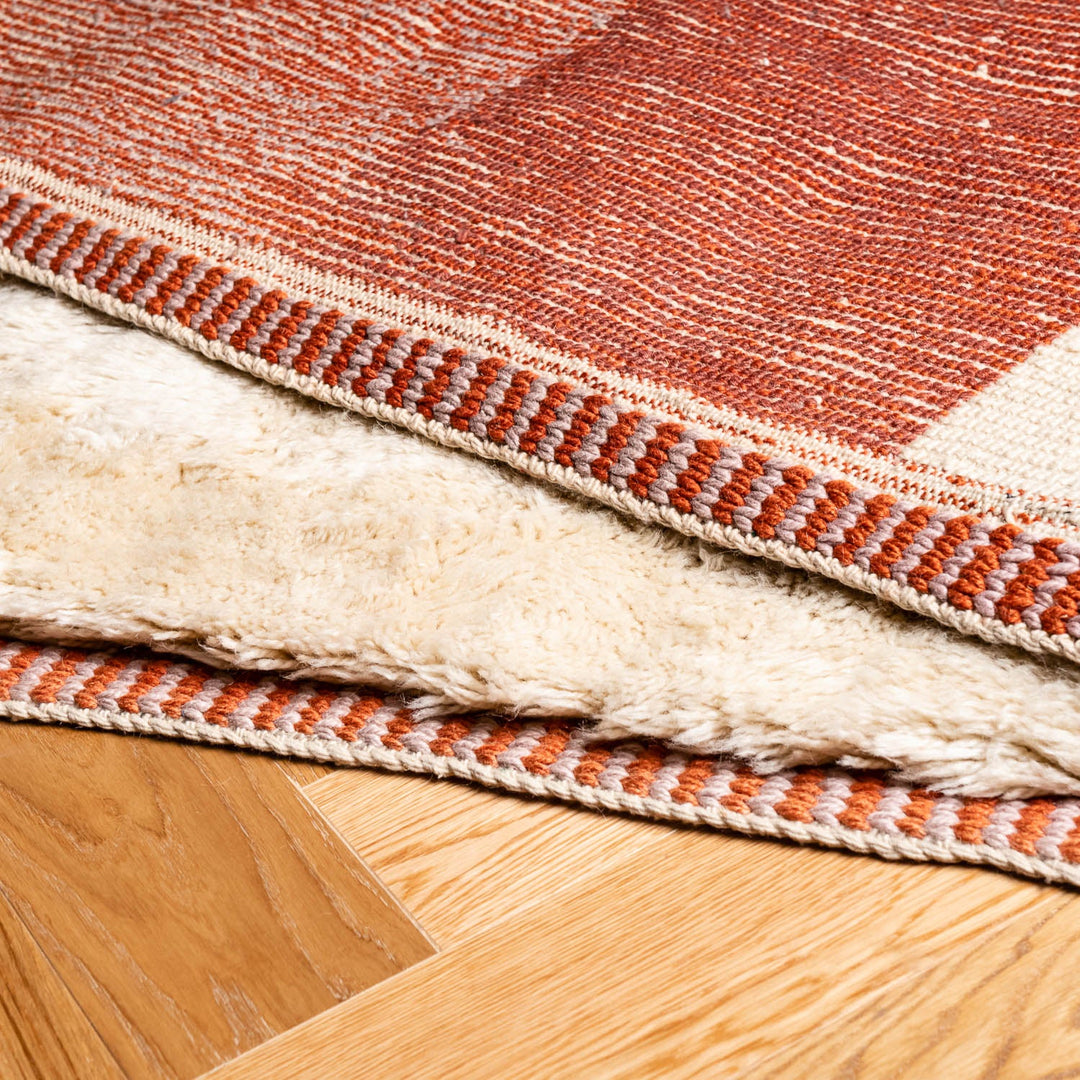 Close-up of a custom Moroccan rug in terracotta, ivory, and black, showcasing rich wool texture and artisan craftsmanship.