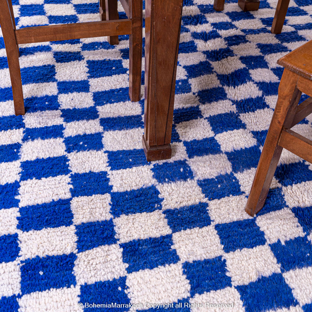 Blue and white checkered Moroccan Berber wool rug under wooden furniture.
