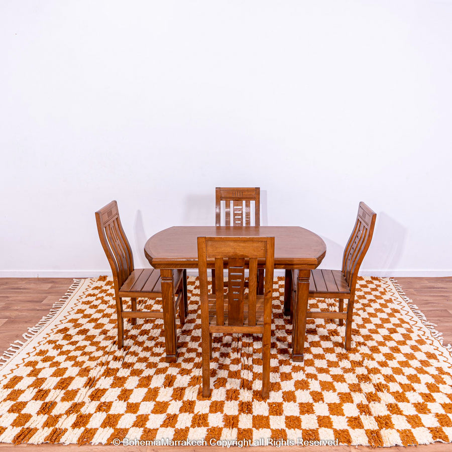 Yellow white checkered Moroccan wool rug under wooden dining set; handcrafted in Atlas Mountains; vibrant traditional design.
