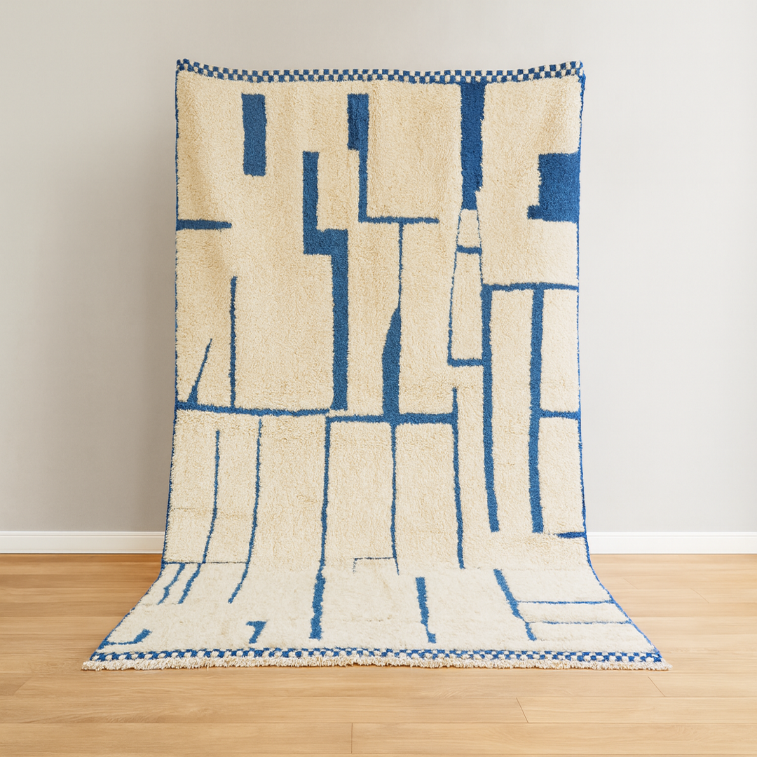 Beige and blue patterned rug on a wooden floor with a white wall background
