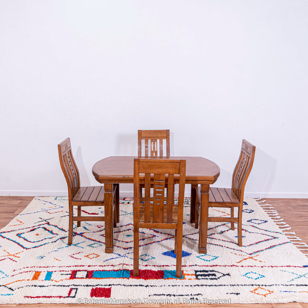 Dining set on colorful Azilal Moroccan wool rug with geometric patterns.