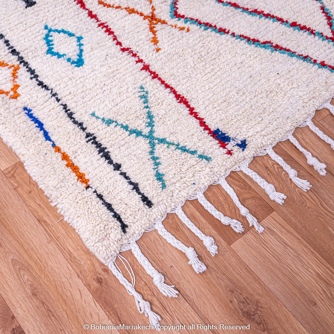 Colorful Azilal Moroccan wool rug with traditional geometric patterns on hardwood floor.