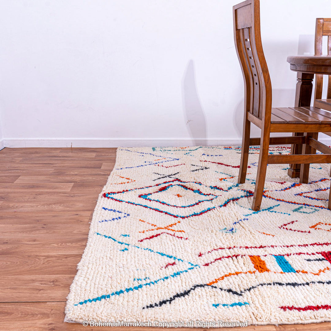 Colorful Azilal Moroccan rug with geometric patterns, handwoven wool carpet on wooden floor, perfect for traditional décor.