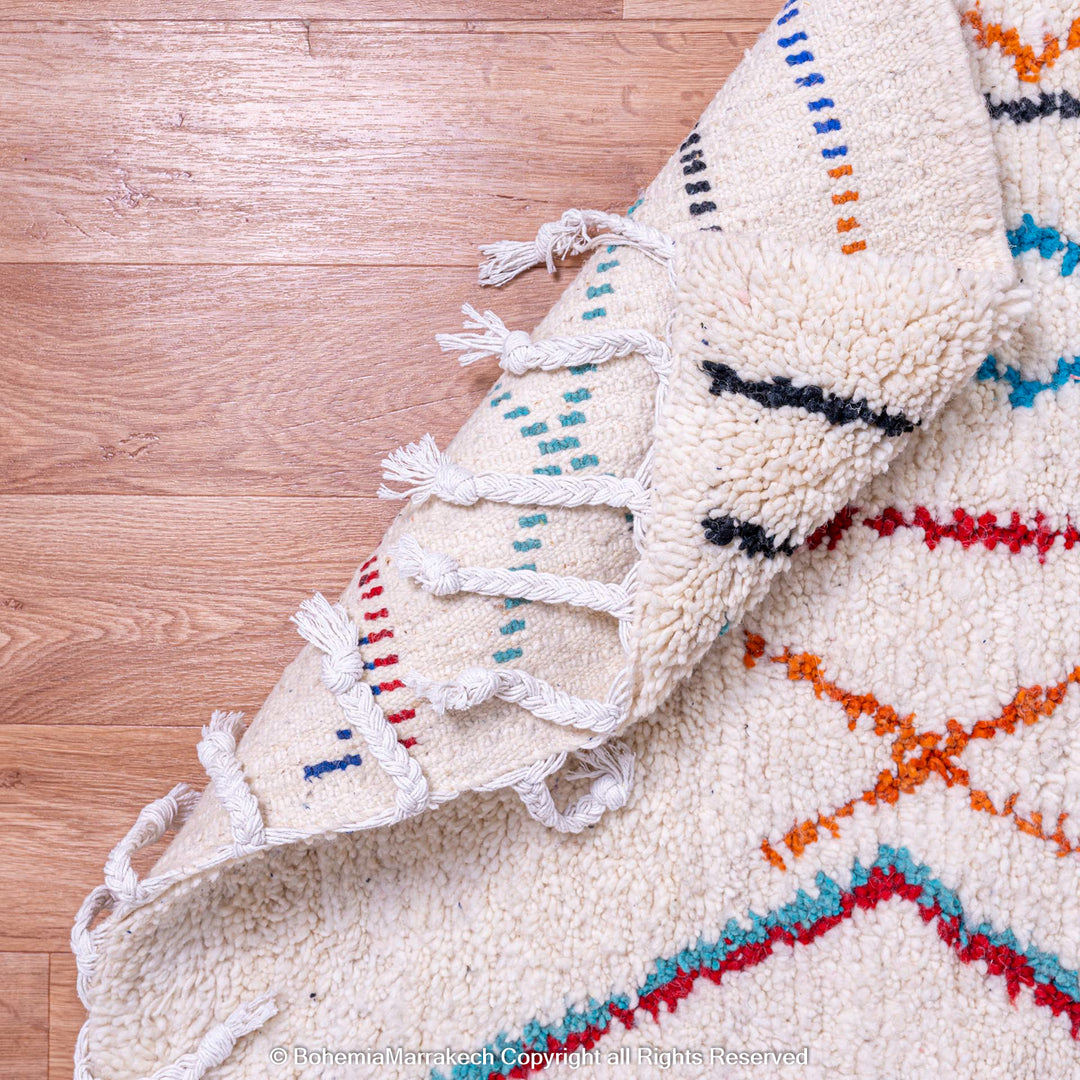 Colorful Azilal Moroccan wool rug with geometric patterns on hardwood floor.
