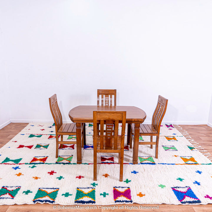 Colorful Moroccan Berber rug with X and cross symbols under a wooden dining table and chairs in a modern room.