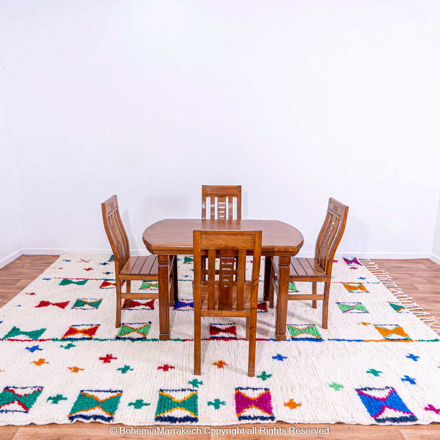 Colorful Moroccan Berber rug with X and cross symbols under a wooden dining table and chairs in a modern room.