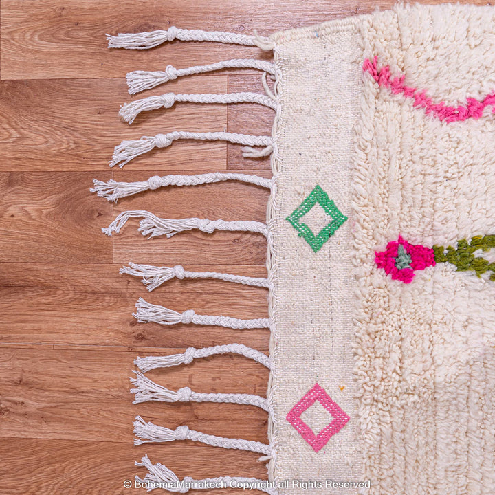 Handwoven Moroccan Berber rug with Azilal diamond motifs in vibrant colors on an ivory background.