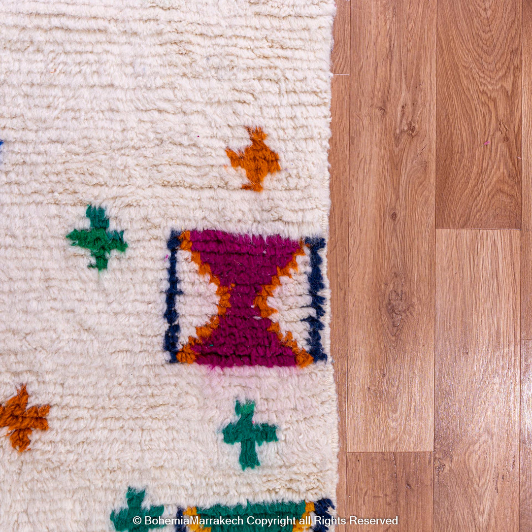 Colorful Moroccan Berber rug with traditional X and cross patterns on an ivory base, showcasing vibrant cultural design