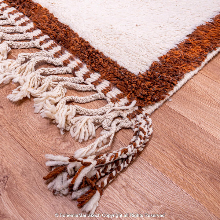 Handmade colorful Moroccan rug with pink, yellow, brown, and green geometric patterns on white wool