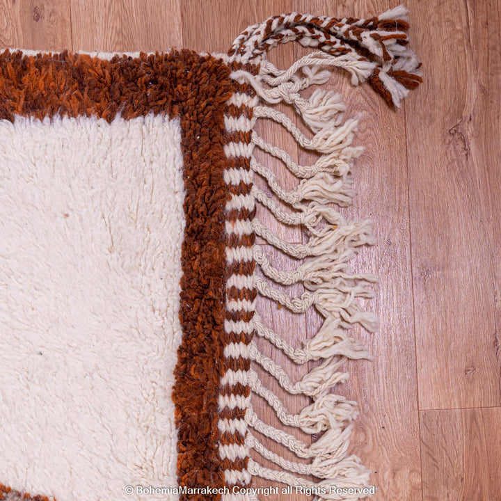 Handmade colorful Moroccan rug with pink, yellow, brown, and green geometric patterns on white wool