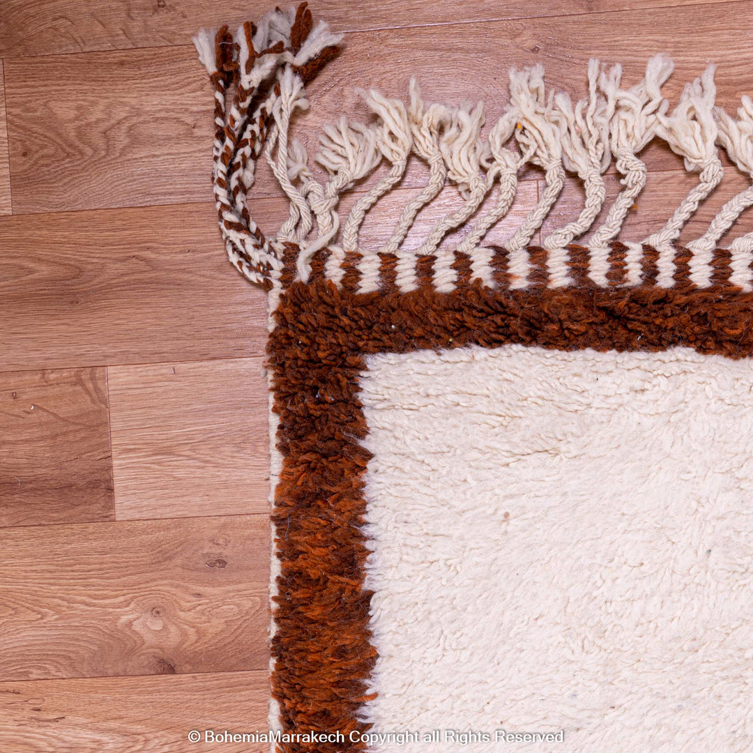 Handmade colorful Moroccan rug with pink, yellow, brown, and green geometric patterns on white wool